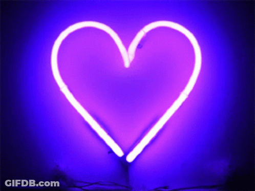 A Purple Neon Heart Is Lit Up On A Wall GIF