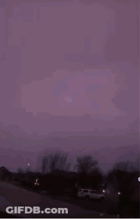 A Purple Sky With Lightning Strikes In The Distance GIF