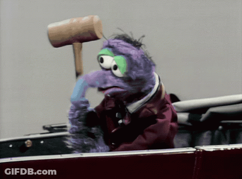 A Purple Stuffed Animal Is Holding A Wooden Mallet On Its Head GIF