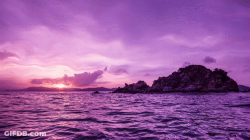 A Purple Sunset Over A Body Of Water With Mountains In The Background GIF