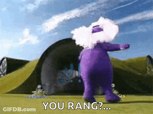 A Purple Teddy Bear Is Standing In Front Of A Building And Says You Rang ? GIF