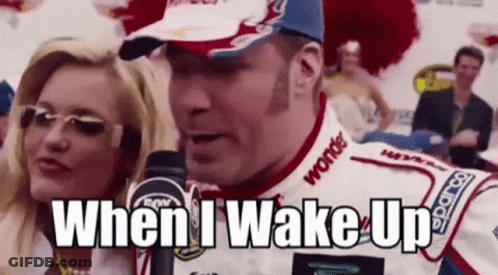 A Race Car Driver Is Talking Into A Microphone While A Woman Stands Behind Him . GIF