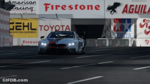 A Race Car Is Driving Down A Road In Front Of Signs For Firestone Toyota And Aguila GIF