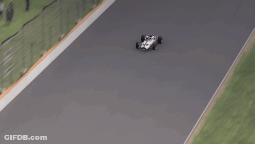 A Race Car Is Driving Down A Track With A Grassy Area In The Background GIF