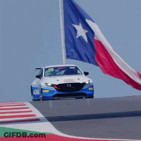 A Race Car Is Driving Down A Track With A Texas Flag Flying In The Background GIF