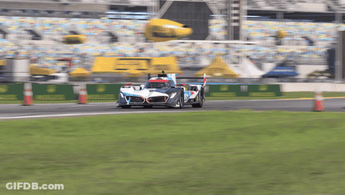 A Race Car Is Driving Down A Track With A Yellow Banner That Says Rolex On It GIF