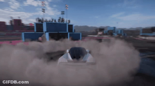 A Race Car Is Driving Down A Track With Smoke Coming Out Of The Back GIF