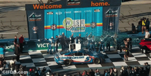 A Race Car Is On A Checkered Race Track With A Banner That Says Welcome Home GIF