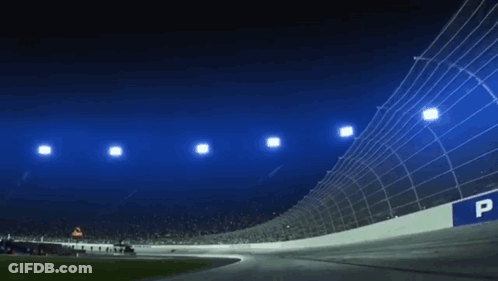 A Race Track Is Lit Up At Night With A Lot Of Lights On It . GIF