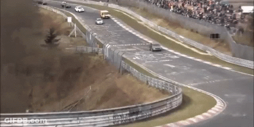 A Race Track With Cars On It And A Crowd In The Background GIF