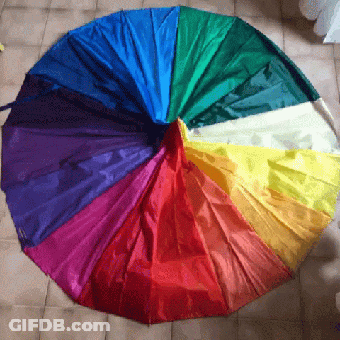 A Rainbow Colored Umbrella Is Laying On A Tile Floor GIF