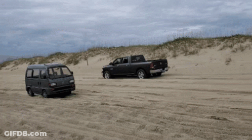 A Ram Truck And A Van Are Parked On A Sandy Beach GIF