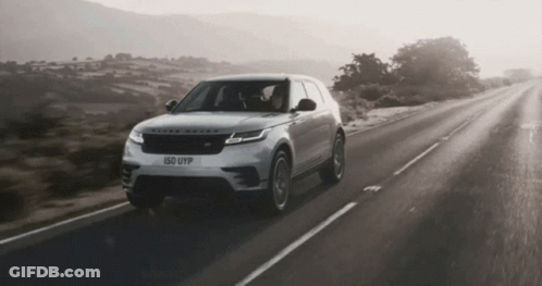 A Range Rover Is Driving Down The Road GIF