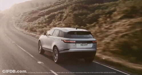 A Range Rover Velar Is Driving Down A Road GIF