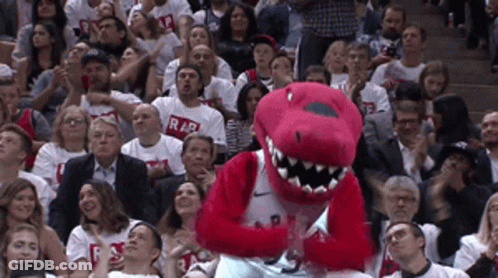 A Raptors Mascot Stands In Front Of A Crowd Of People Wearing Raptors Shirts GIF