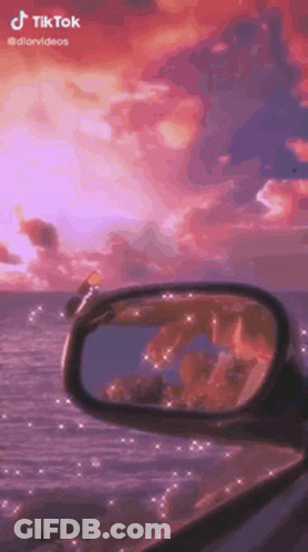 A Rear View Mirror Of A Car With A Sunset In The Background . GIF