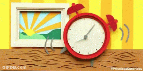 A Red Alarm Clock Is Sitting On A Wooden Table Next To A Picture And A Picture Frame . GIF