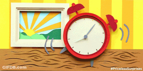 A Red Alarm Clock Sits On A Wooden Table Next To A Picture GIF
