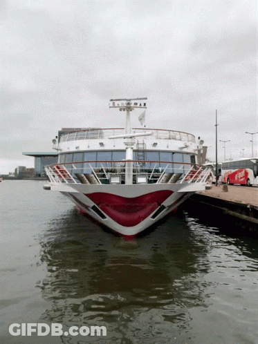 A Red And White Cruise Ship Is Docked At A Pier GIF