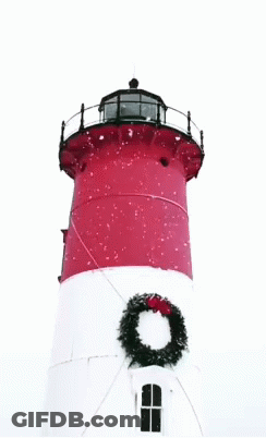 A Red And White Lighthouse With A Wreath On Top GIF