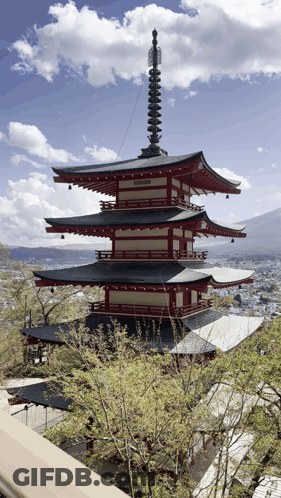 A Red And White Pagoda With A Clock On Top GIF