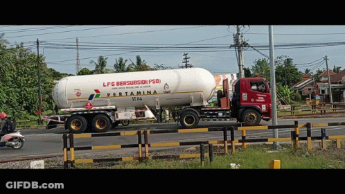 A Red And White Pertamina Truck Is Driving Down A Road GIF