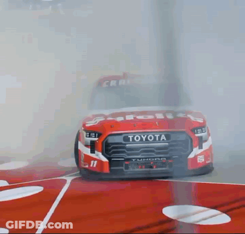 A Red And White Toyota Truck Is Driving On A Race Track GIF
