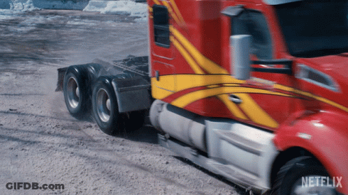 A Red And Yellow Semi Truck Is Driving Down A Dirt Road With Netflix Written On The Bottom GIF