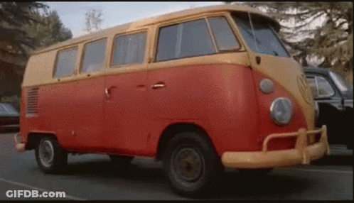 A Red And Yellow Van Is Parked On The Side Of A Road . GIF