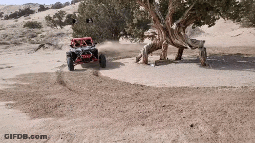 A Red Atv Is Driving Down A Dirt Road GIF