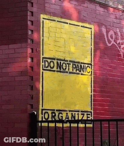 A Red Brick Wall With A Yellow Sign That Says Do Not Panic GIF