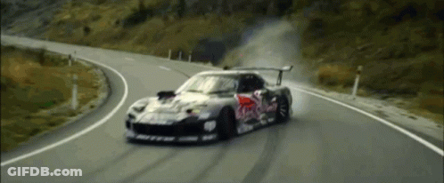 A Red Bull Race Car Is Driving Down A Curvy Road GIF
