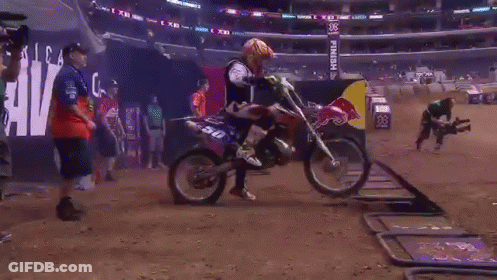 A Red Bull Sign Is In The Background Of A Dirt Track GIF