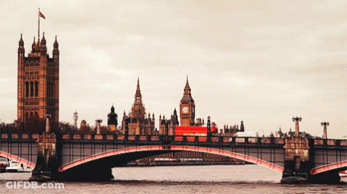 A Red Bus Is Crossing A Bridge In Front Of Big Ben In London GIF