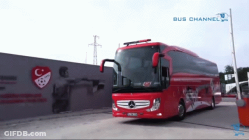A Red Bus Is Parked In Front Of A Wall With A C And A Soccer Ball On It GIF