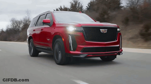 A Red Cadillac Is Driving Down A Highway GIF