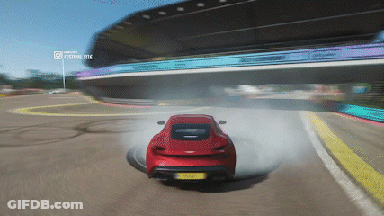 A Red Car Is Drifting On A Race Track With A Festival Site Displayed In The Background GIF