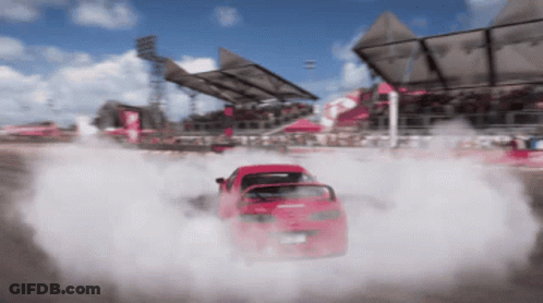 A Red Car Is Drifting On A Race Track With Smoke Coming Out Of It GIF