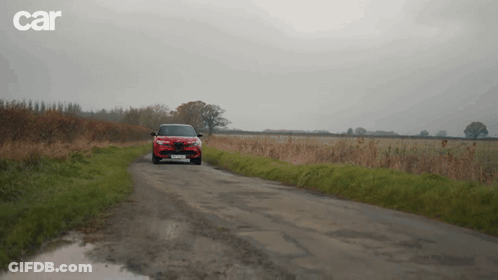 A Red Car Is Driving Down A Dirt Road With Car Written On The Bottom Right GIF