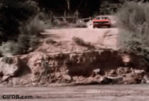 A Red Car Is Driving Down A Dirt Road With Trees In The Background GIF