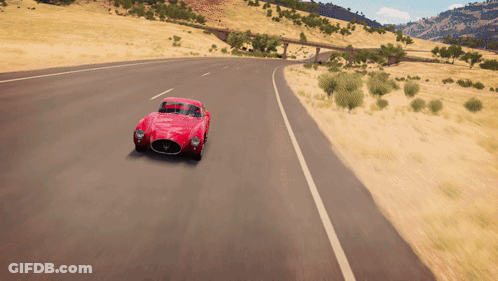 A Red Car Is Driving Down A Road With A Bridge In The Background GIF