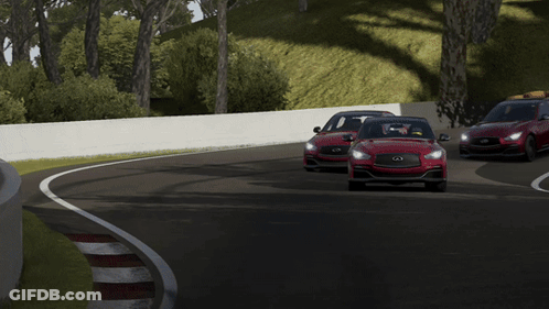 A Red Car Is Driving Down A Road With A White Wall Behind It GIF