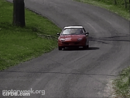 A Red Car Is Driving Down A Road With Motorweek.org Written On The Bottom Right GIF