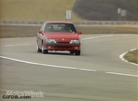 A Red Car Is Driving Down A Road With Motorweek Written On The Bottom Of The Screen GIF