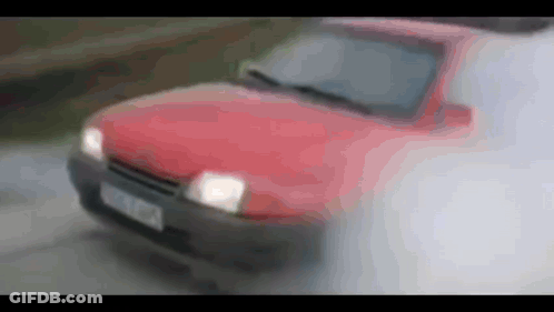 A Red Car Is Driving Down A Road With Smoke Coming Out Of The Hood And Windshield GIF
