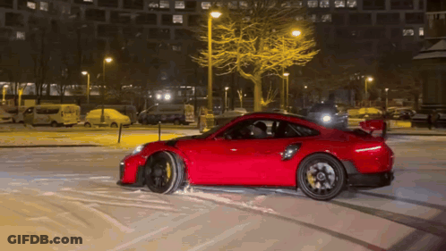 A Red Car Is Driving In The Snow At Night GIF