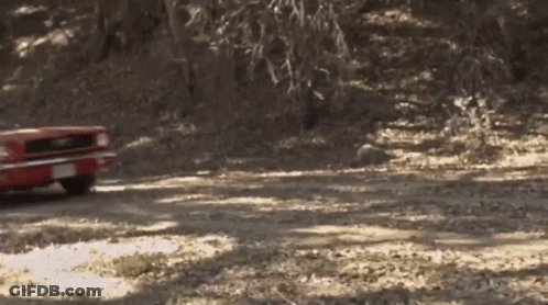 A Red Car Is Driving On A Dirt Road GIF