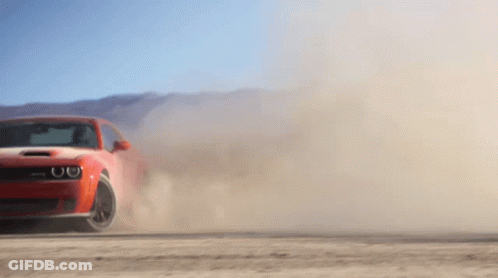 A Red Car Is Driving On A Dirt Road And Kicking Up Dust GIF