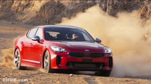 A Red Car Is Driving On A Dirt Road GIF
