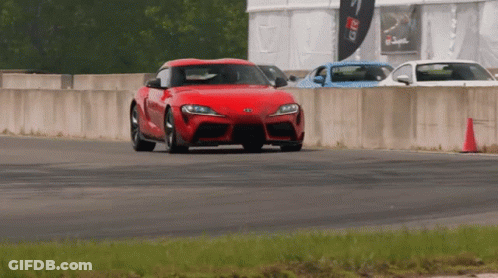 A Red Car Is Driving On A Track With A Sign That Says Greddy GIF